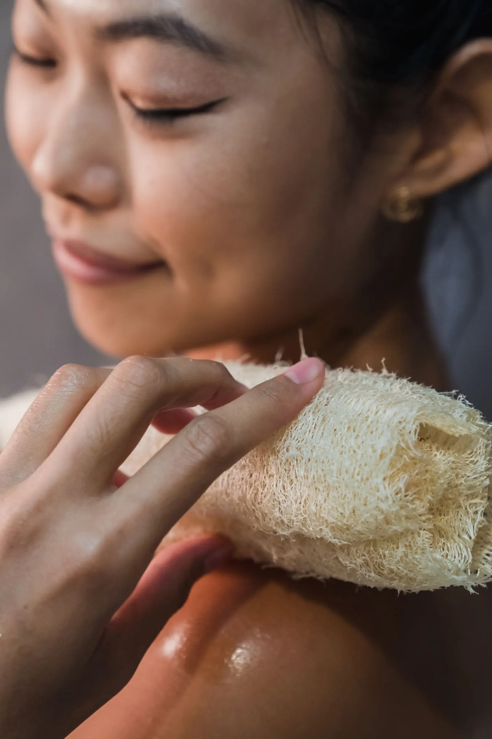 A woman washing her shoulder with a natural loofah