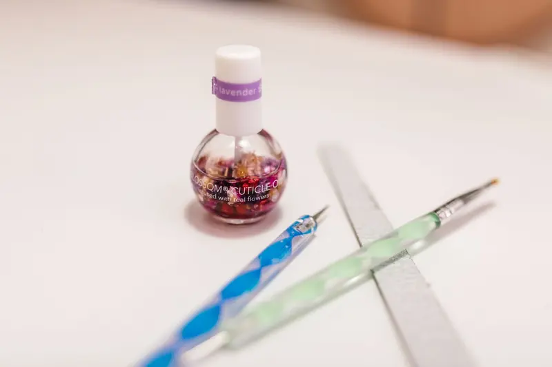 Cuticle oil bottle beside colorful manicure tools