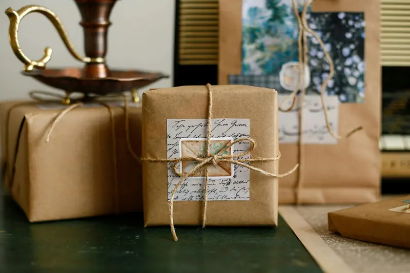 Brown paper gift boxes tied with twine beside a brass lamp