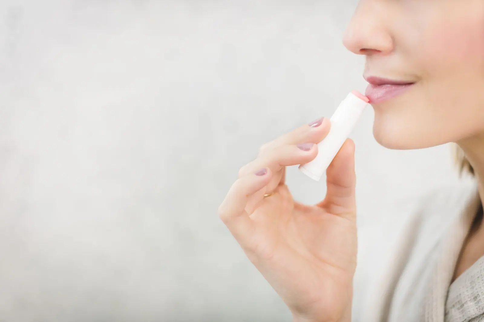 A woman applying lip balm to her lips