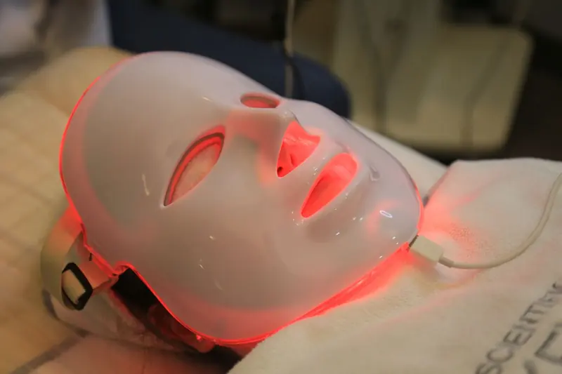 A person wearing a white face mask illuminated with red light