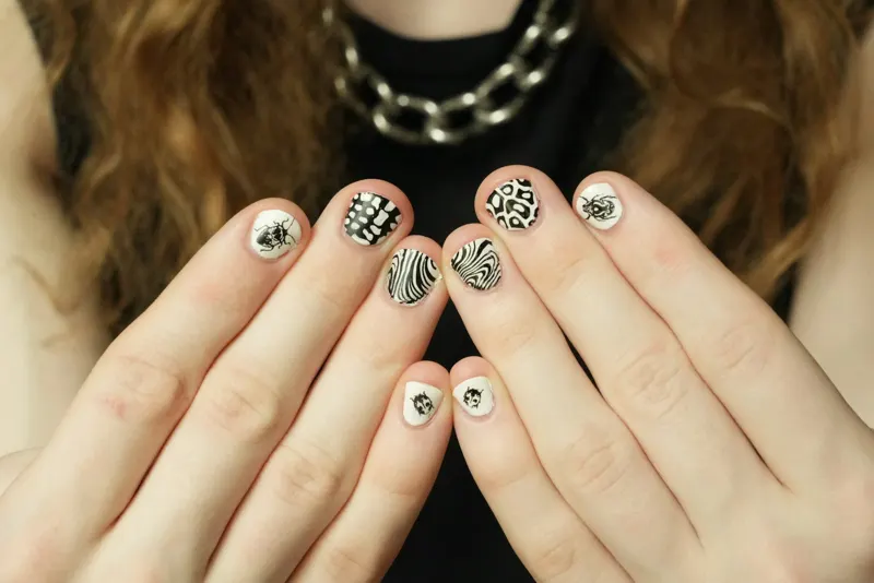 Hands displaying black-and-white animal-pattern nail art