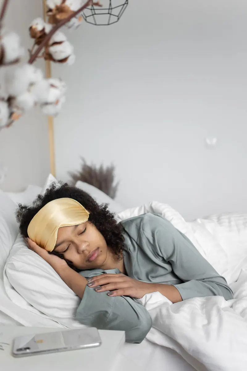 A woman resting in bed with a yellow sleep mask