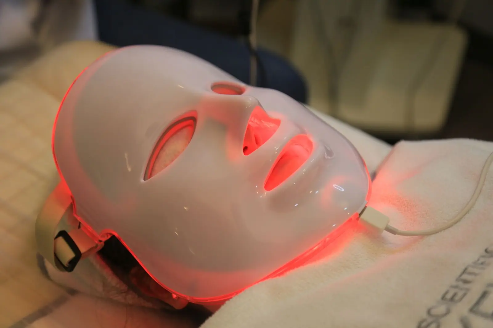 A person wearing a white face mask illuminated with red light