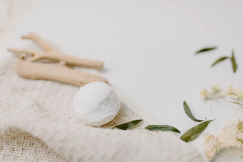 A white bath bomb with driftwood and leafy branches on fabric