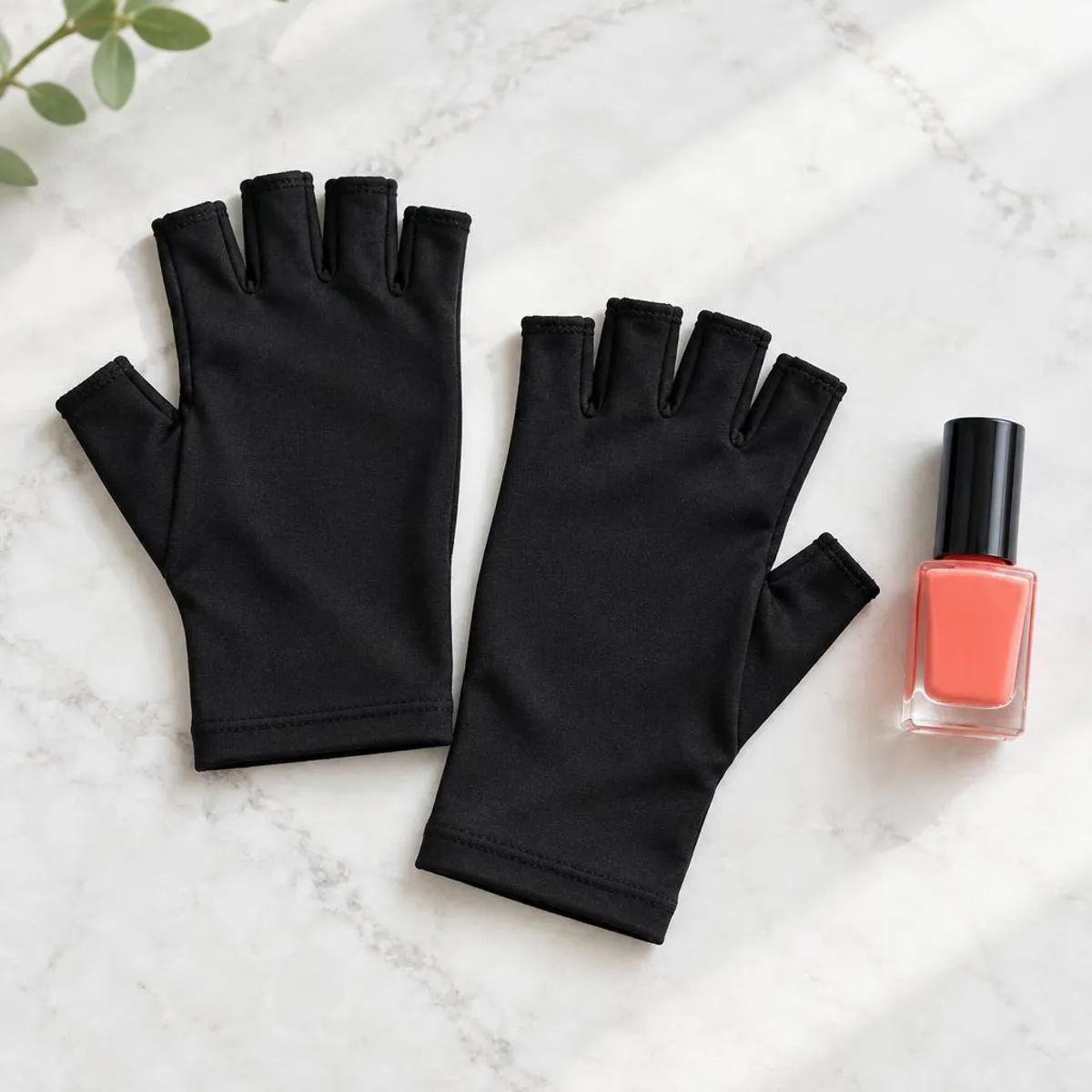 Illustrative photo: Plain black fingerless gloves beside a coral polish bottle